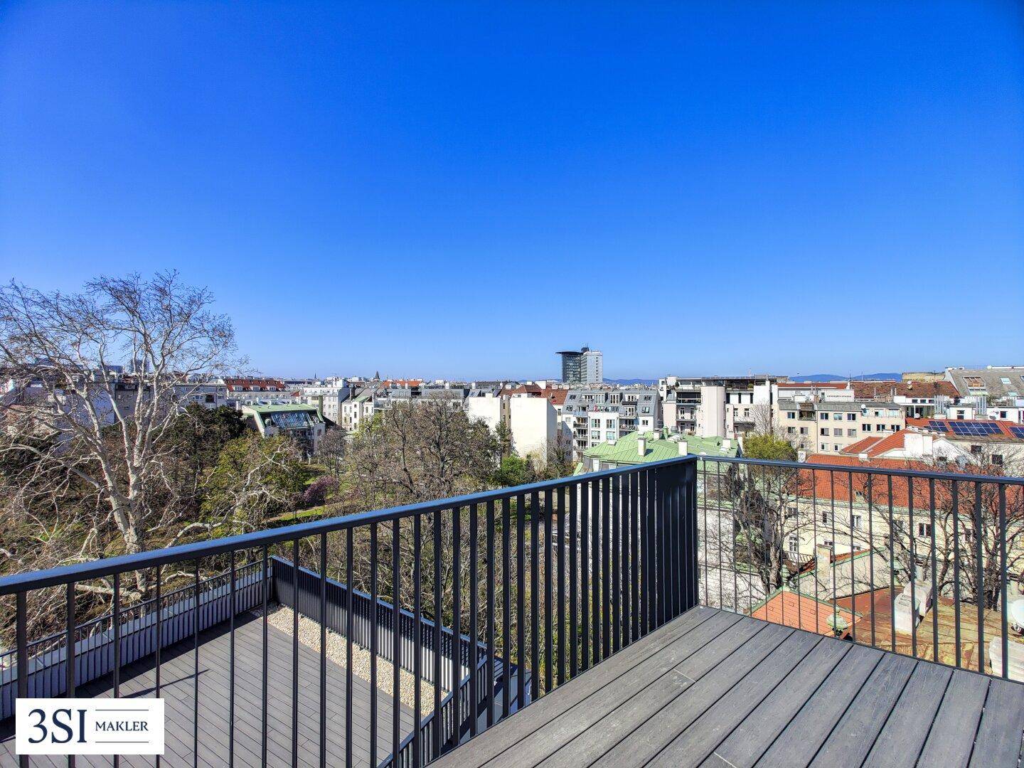 Dachterrasse mit modernem Bodenbelag und Blick auf die umliegende Stadtlandschaft und Bäume.