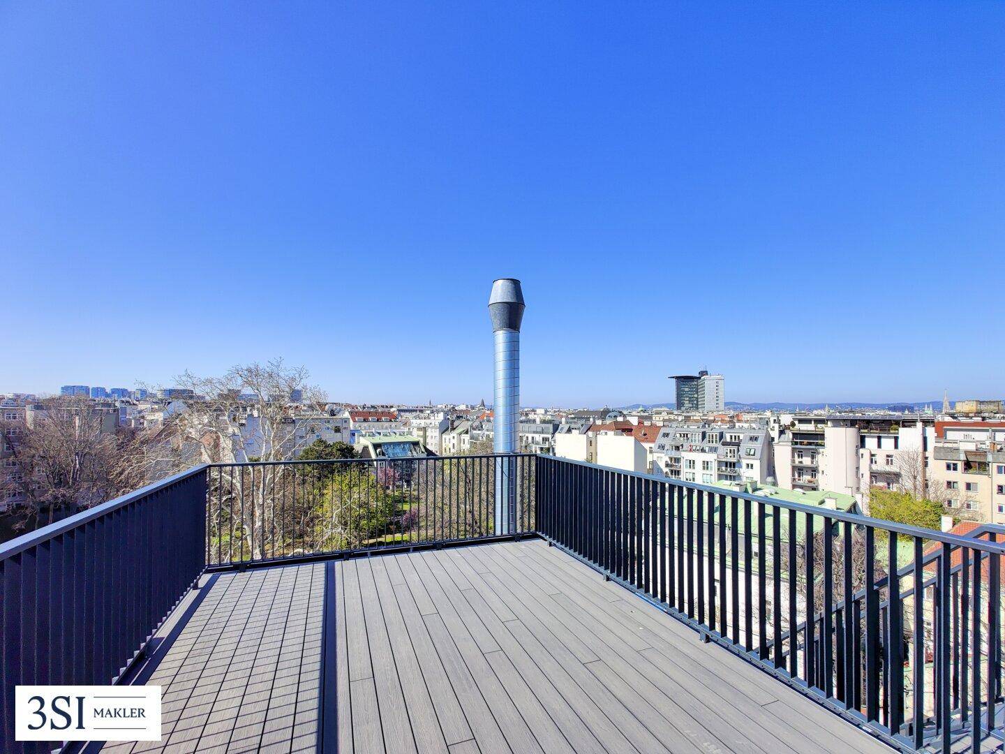 Weitläufige Dachterrasse mit modernem Bodenbelag und unverbautem Blick über die Stadt.