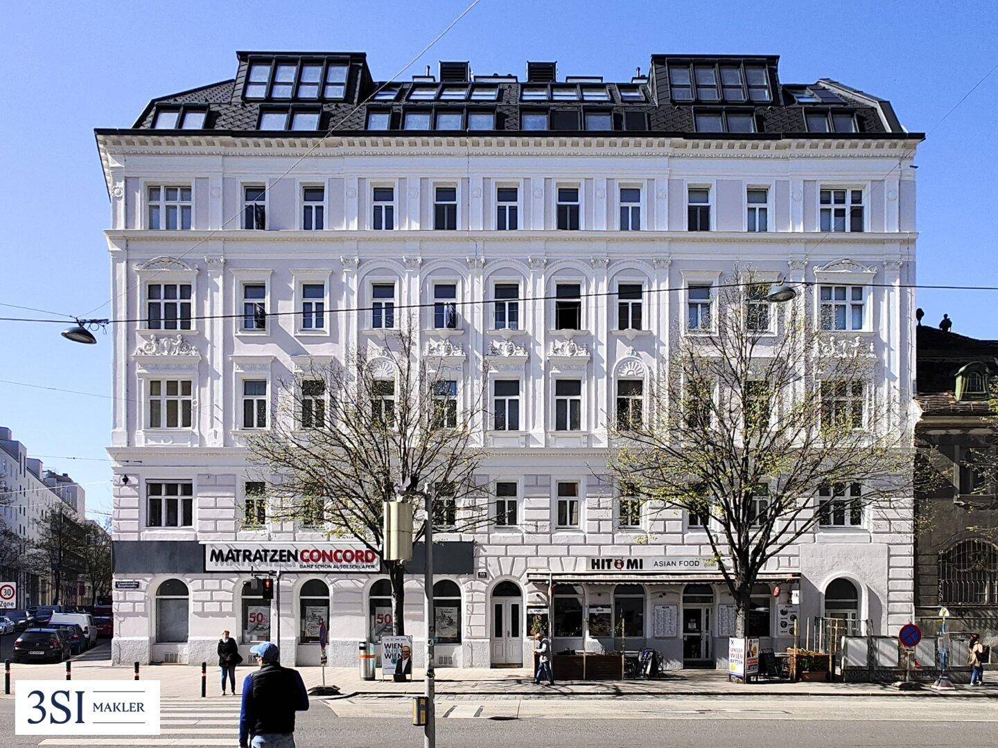 Historisches Gebäude mit klassischer Fassade und modernen Dachgauben in städtischer Umgebung.