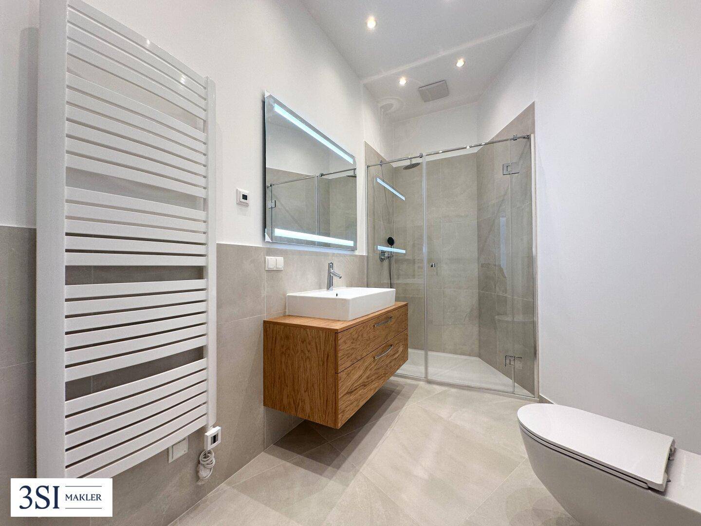 Modernes Badezimmer mit ebenerdiger Dusche, Einzelwaschbecken und beheiztem Handtuchhalter.