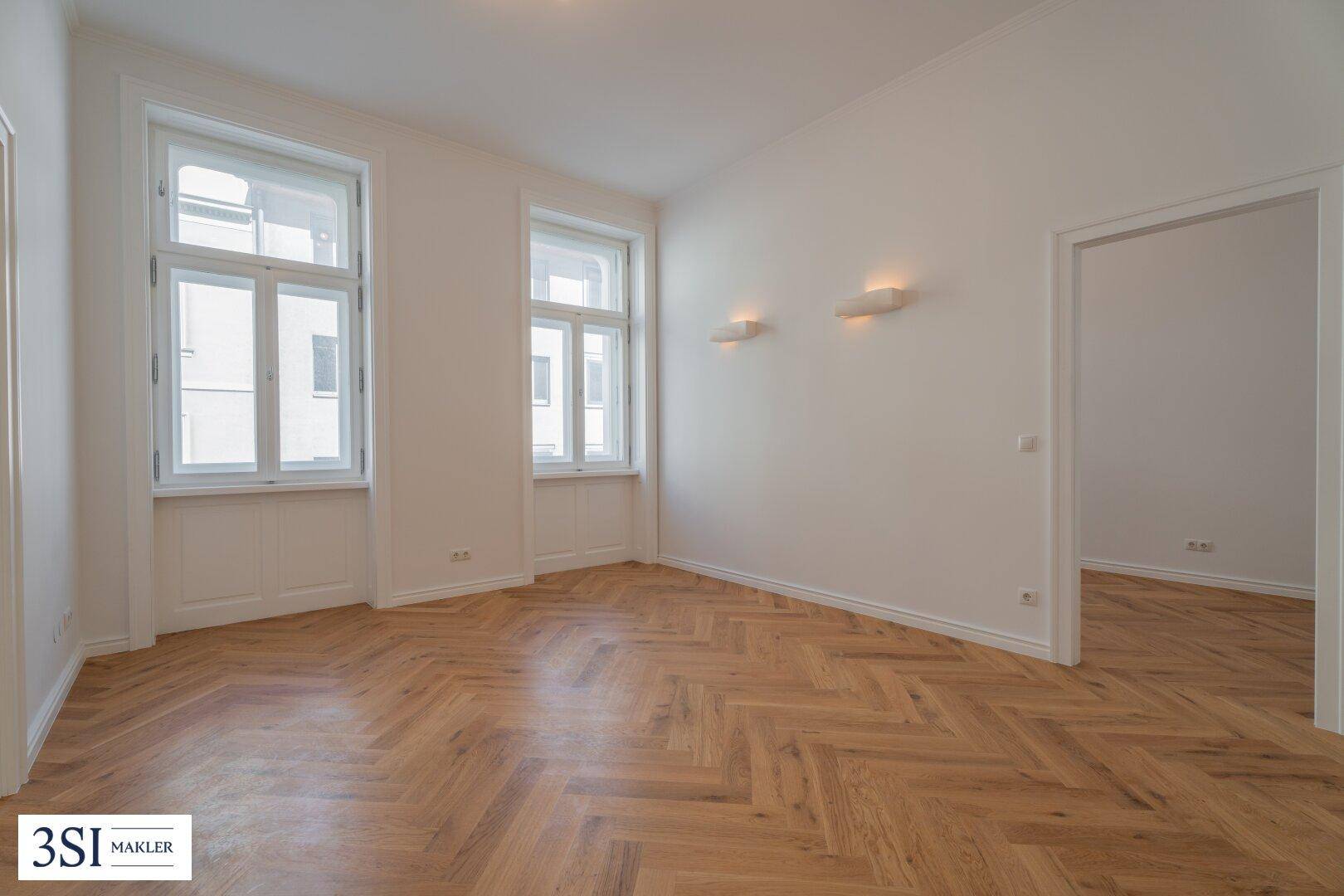 Heller Raum mit klassischem Fischgrätparkett und hohen Fenstern, bereit zur individuellen Gestaltung.