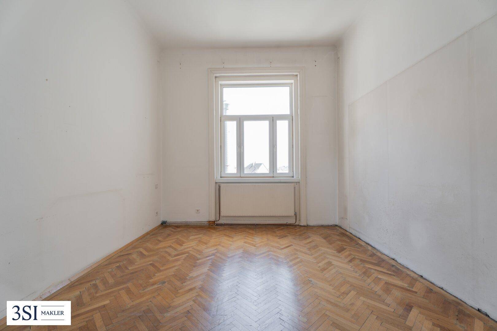 Ruhiges Zimmer mit Fischgrätparkett und einem großen Fenster für viel Licht.