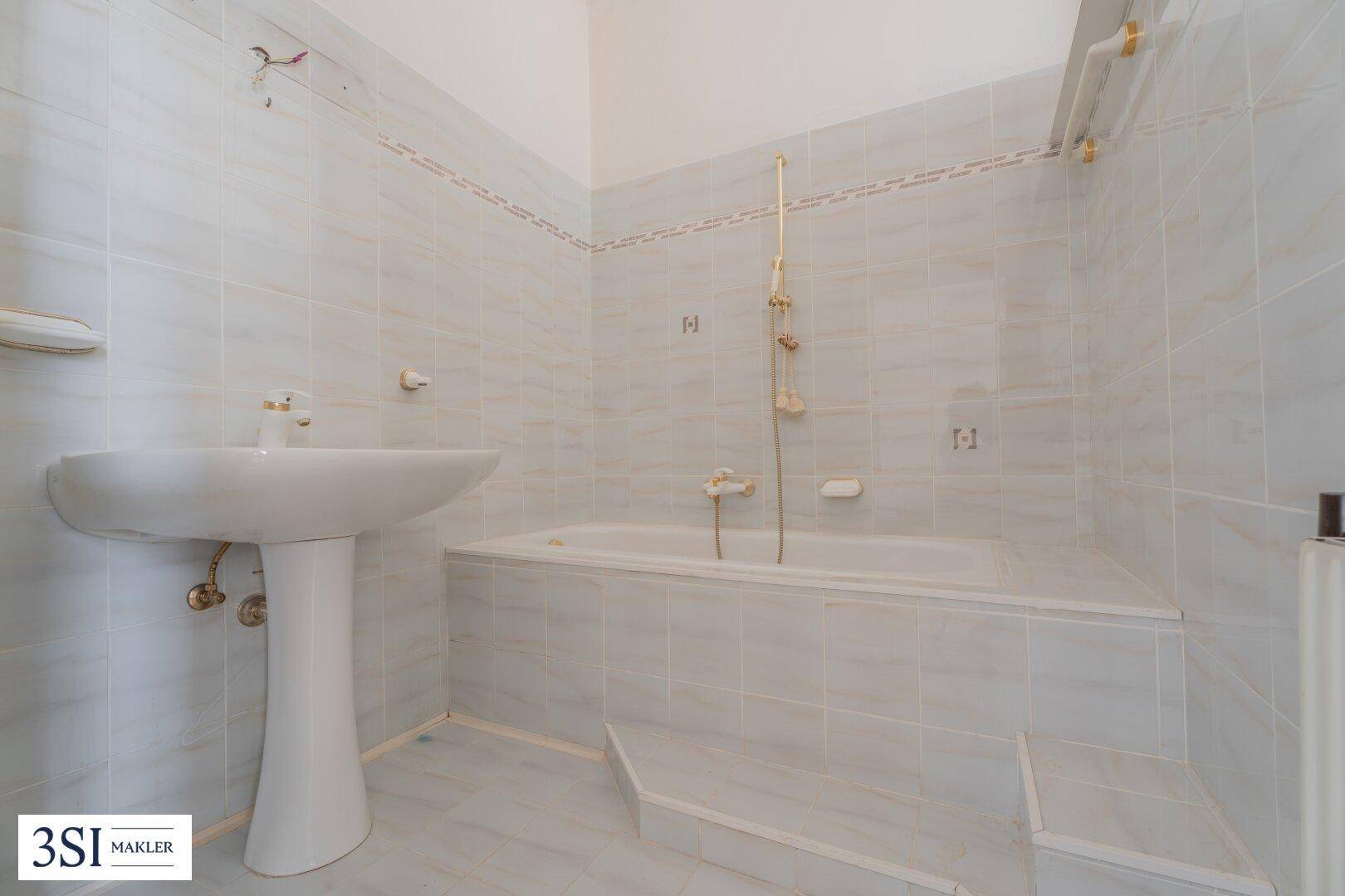 Badezimmer mit Badewanne, Waschbecken und hellblauen Fliesen im klassischen Stil.