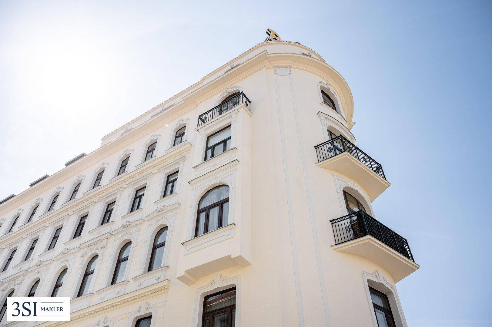 Detailaufnahme der eleganten Fassade mit geschwungenen Balkonen und Stuckverzierungen.