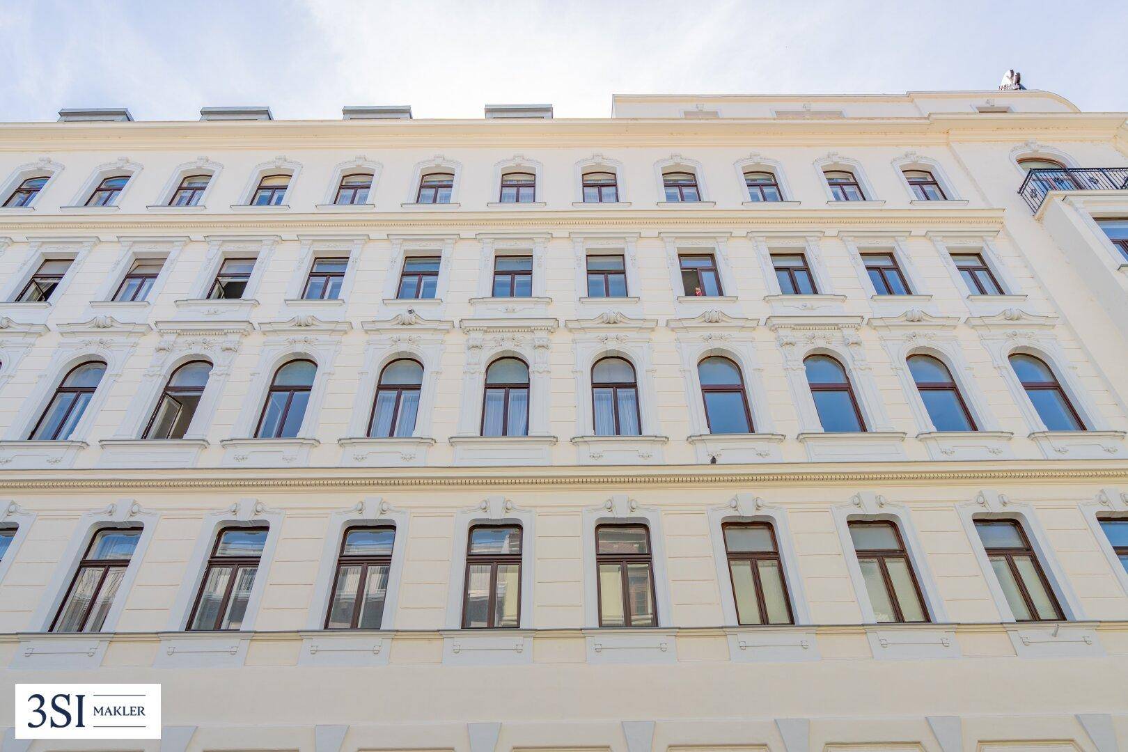 Reihen von Fenstern an der hellen Fassade des Gebäudes unter klarem Himmel.