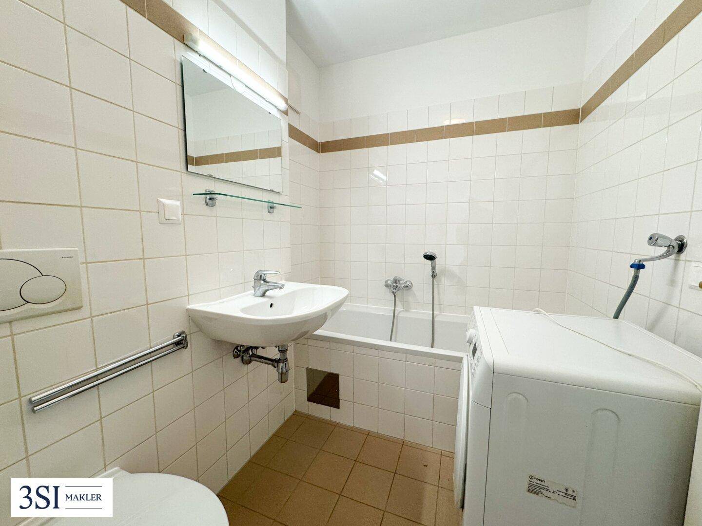 Funktionales Badezimmer mit Badewanne, Waschbecken, WC und Waschmaschine, hell gefliest mit Haltegriffen.