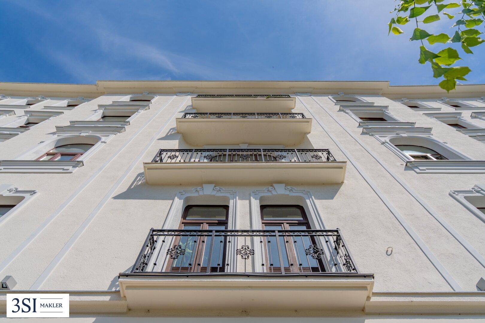 Nahaufnahme der Fassade mit verzierten Balkongeländern und eleganten Fenstern des historischen Gebäudes.