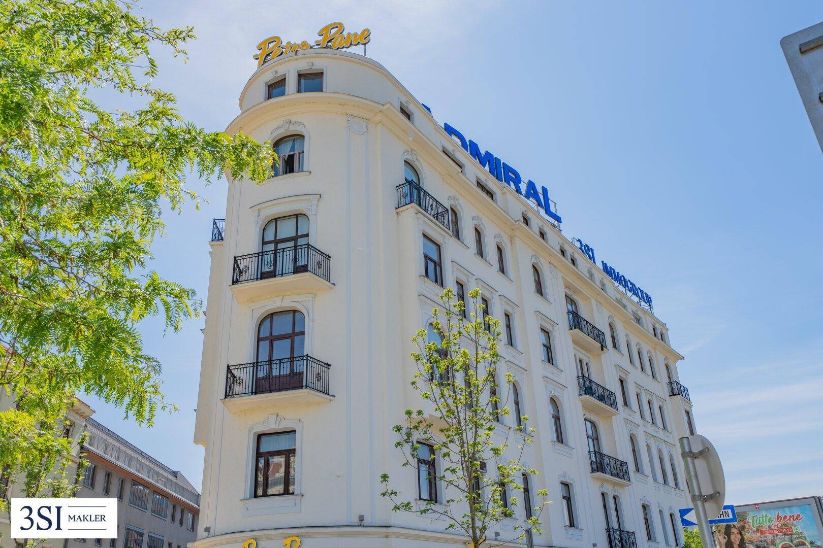 Elegantes Eckgebäude mit geschwungener Fassade, kleinen Balkonen und klassischer Architektur.