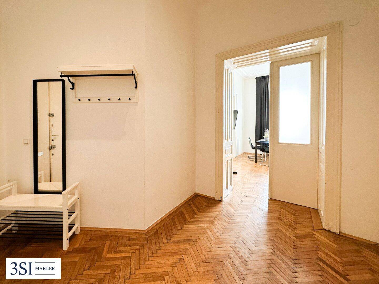 Geräumiger Flur mit Fischgrätparkett, Garderobe und Zugang zu weiteren Wohnräumen.