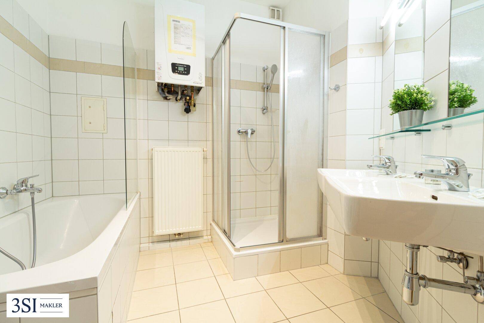 Funktionales Badezimmer mit Badewanne, Duschkabine, Doppelwaschbecken und Wandfliesen.