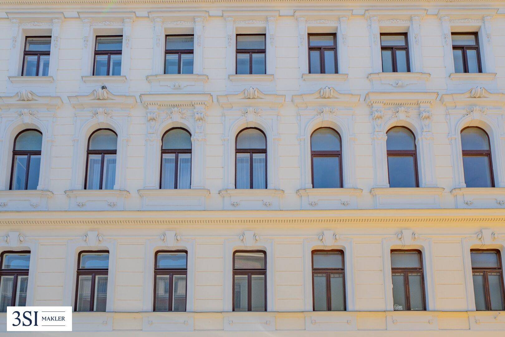 Detailansicht einer historischen Fassade mit verzierten Fenstern und Stuckelementen.