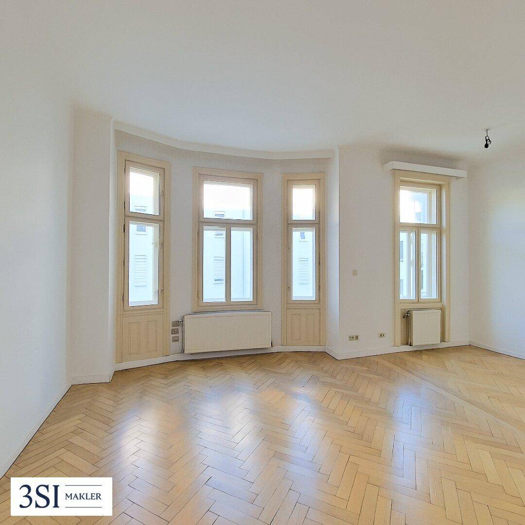 Heller Wohnraum mit Fischgrätparkett und großen Fenstern, bereit zur individuellen Gestaltung.