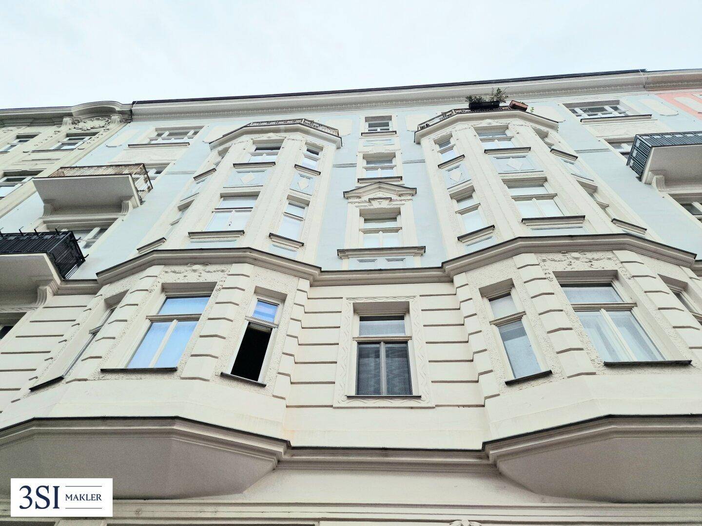 Historische Fassade eines Mehrfamilienhauses mit Erkern und dekorativen Elementen.
