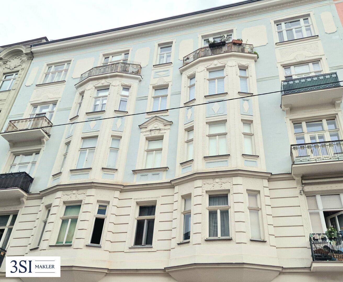 Elegante Fassade eines Altbaus mit mehreren Balkonen und Erkerfenstern.