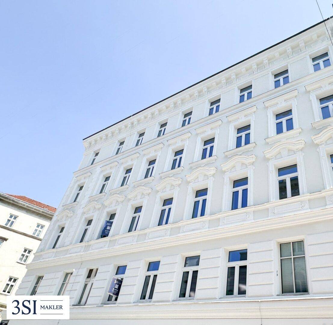 Schrägansicht der strahlend weißen Fassade eines historischen Gebäudes mit vielen Fenstern und klarem Himmel.