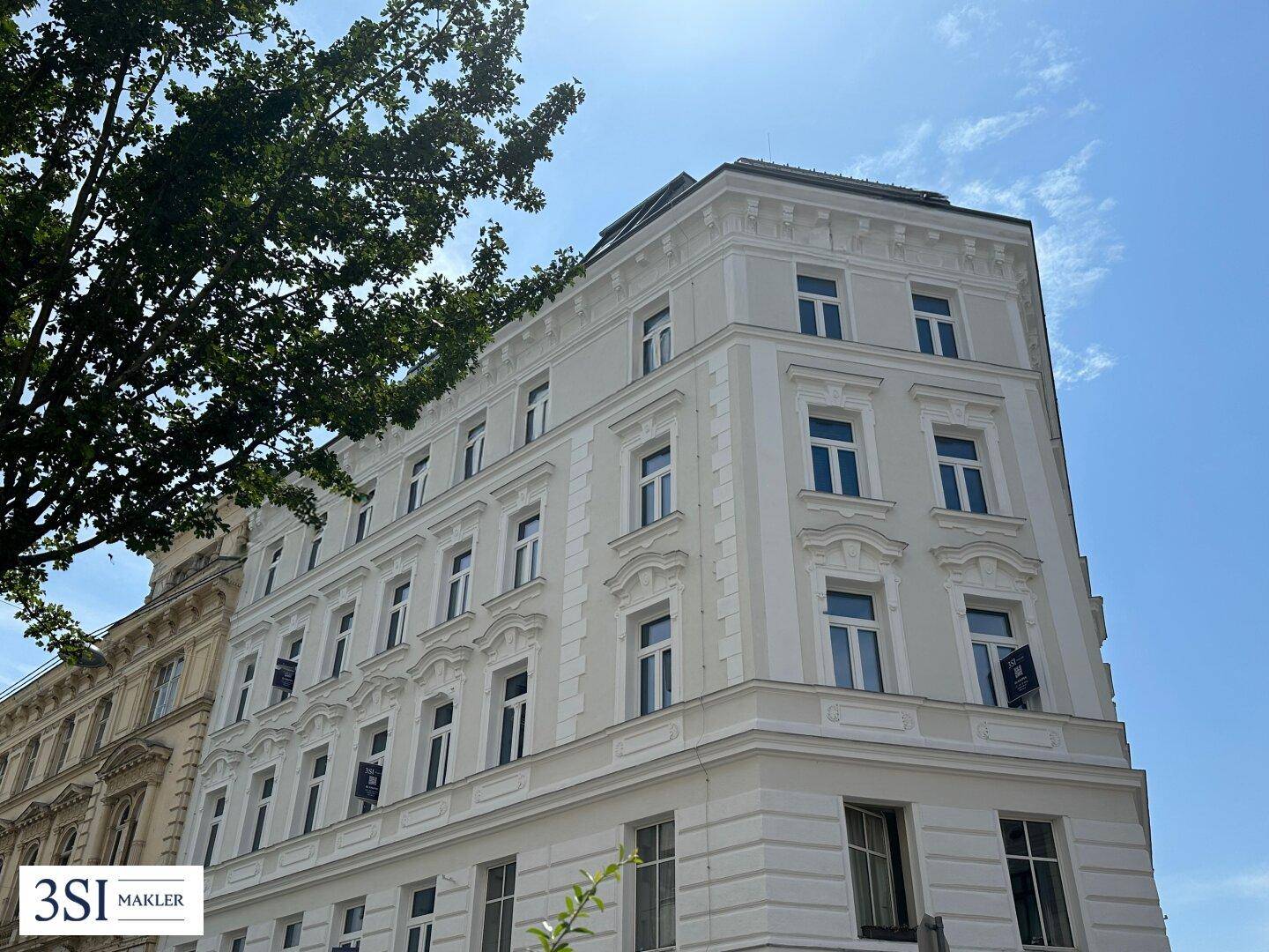 Eindrucksvolle Eckfassade eines historischen Gebäudes mit detailreichen Verzierungen und blauem Himmel.