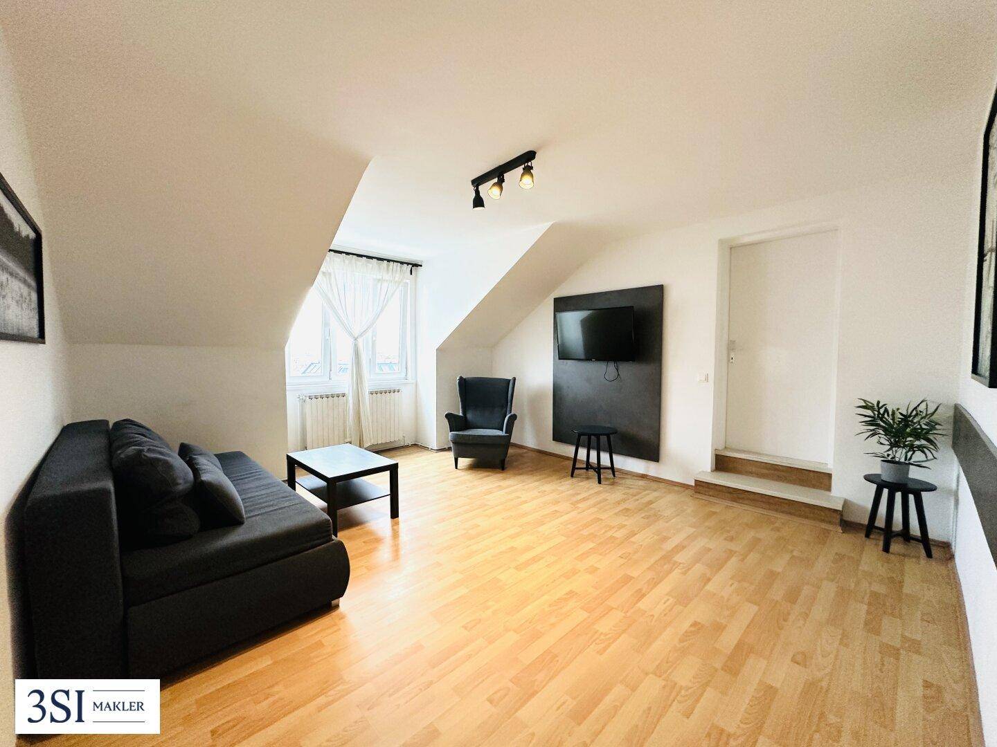 Helles Wohnzimmer mit Dachschrägen, Holzboden und gemütlicher Einrichtung im Dachgeschoss.