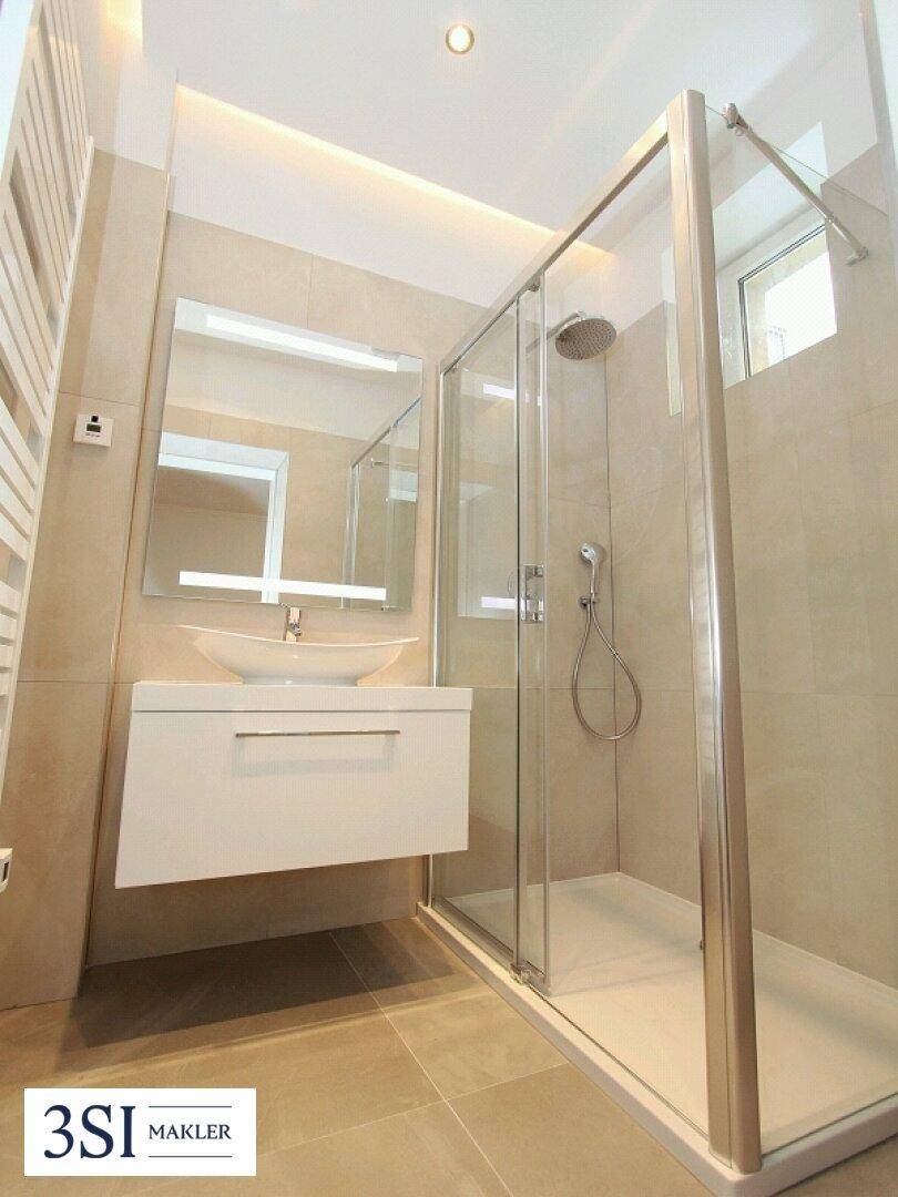 Modernes Badezimmer mit begehbarer Dusche, schwebendem Waschtisch und beheiztem Handtuchhalter.