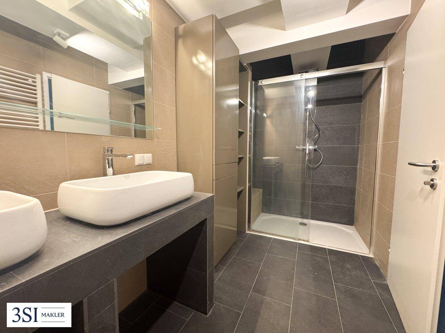 Modernes Badezimmer mit großer Duschkabine, Einzelwaschbecken und beigefarbenen Fliesen.