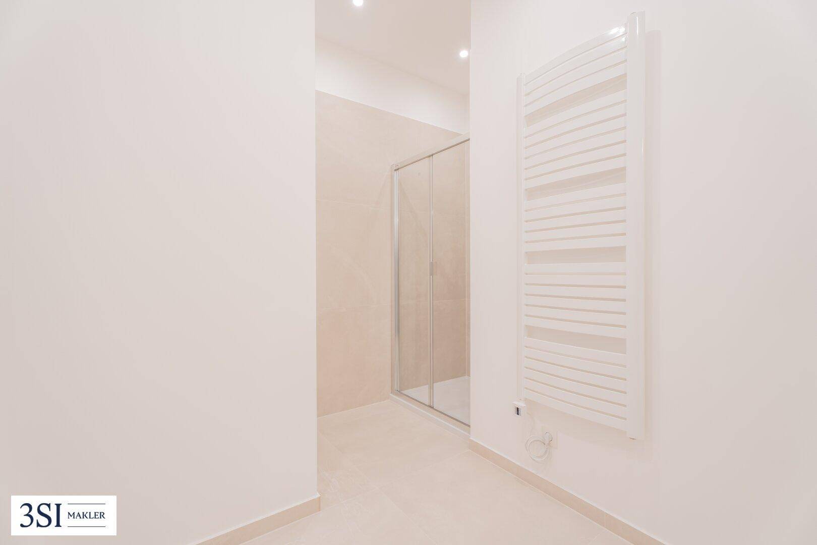 Modernes Badezimmer mit begehbarer Dusche, Glasabtrennung und beheiztem Handtuchtrockner.