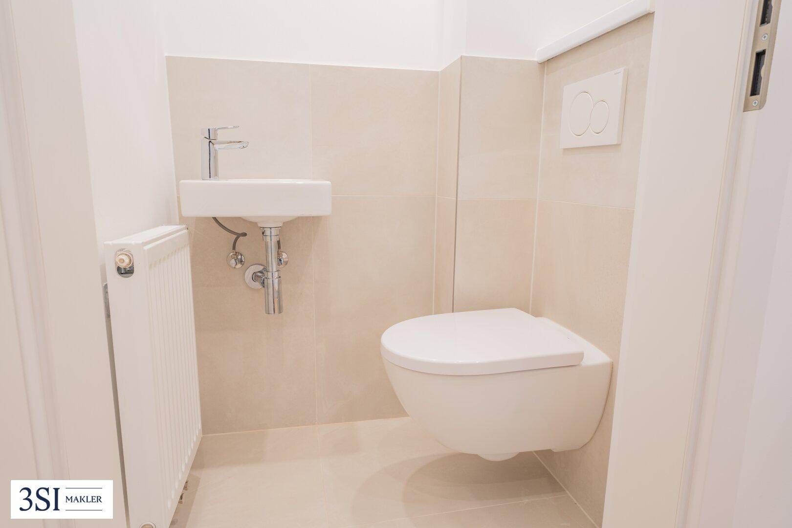Separates Gäste-WC mit wandhängender Toilette und kleinem Waschbecken.