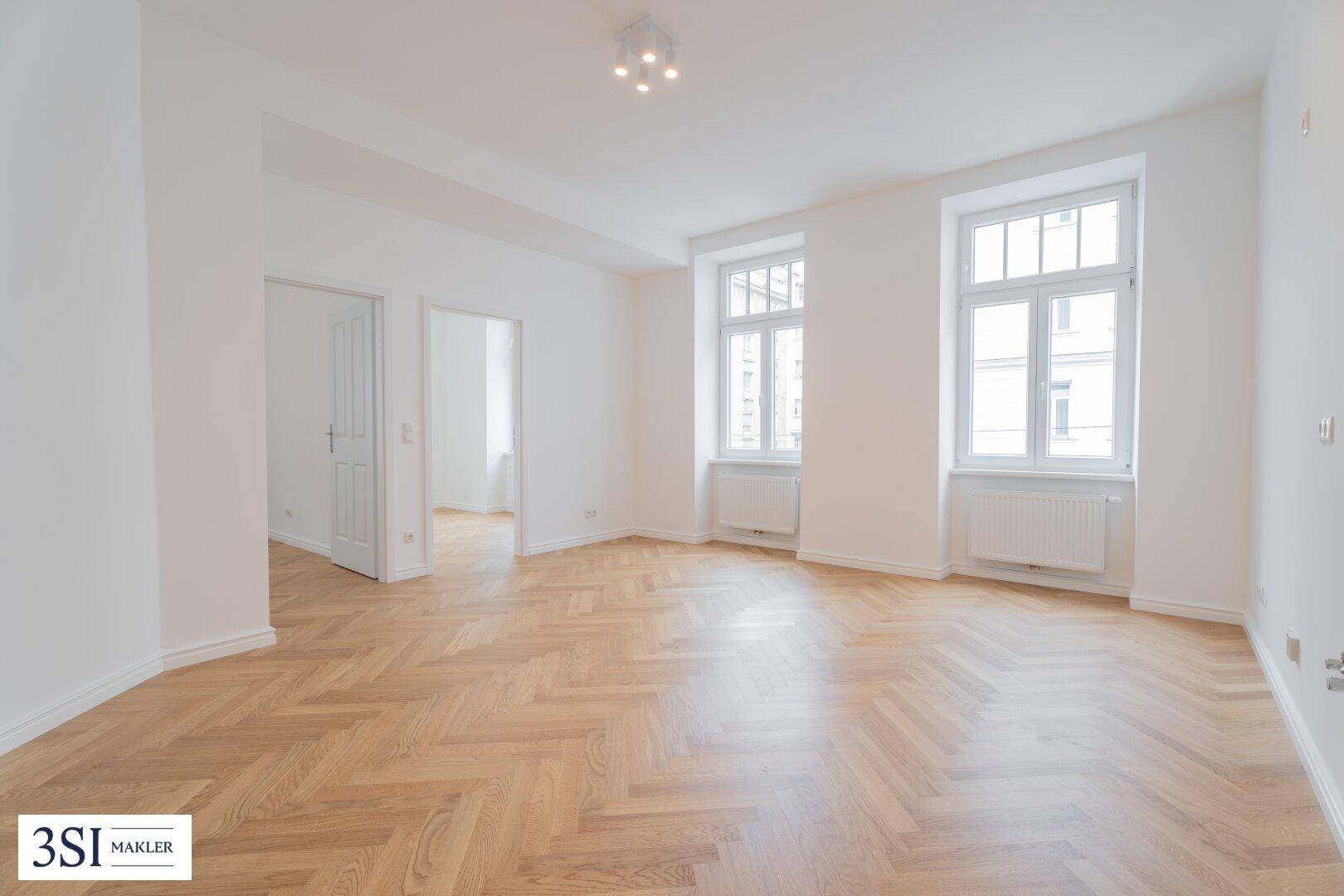 Geräumiges, helles Zimmer mit Fischgrätparkett, hohen Decken und Blick auf die Umgebung.