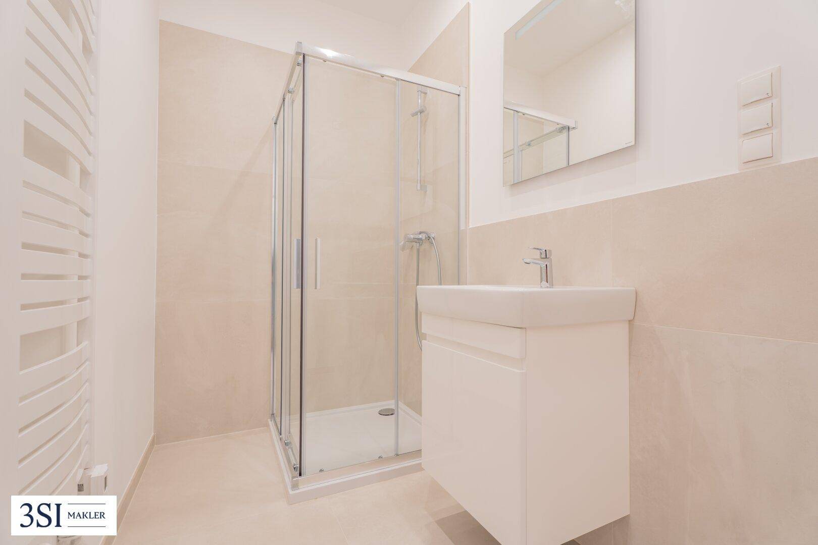 Modernes Badezimmer mit Duschkabine, Waschbecken und beheiztem Handtuchhalter.