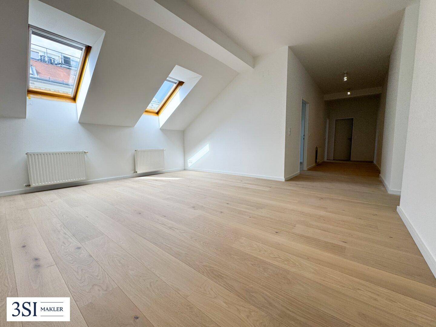Helles Dachgeschosszimmer mit Holzboden und Dachfenstern, bereit für die individuelle Gestaltung.