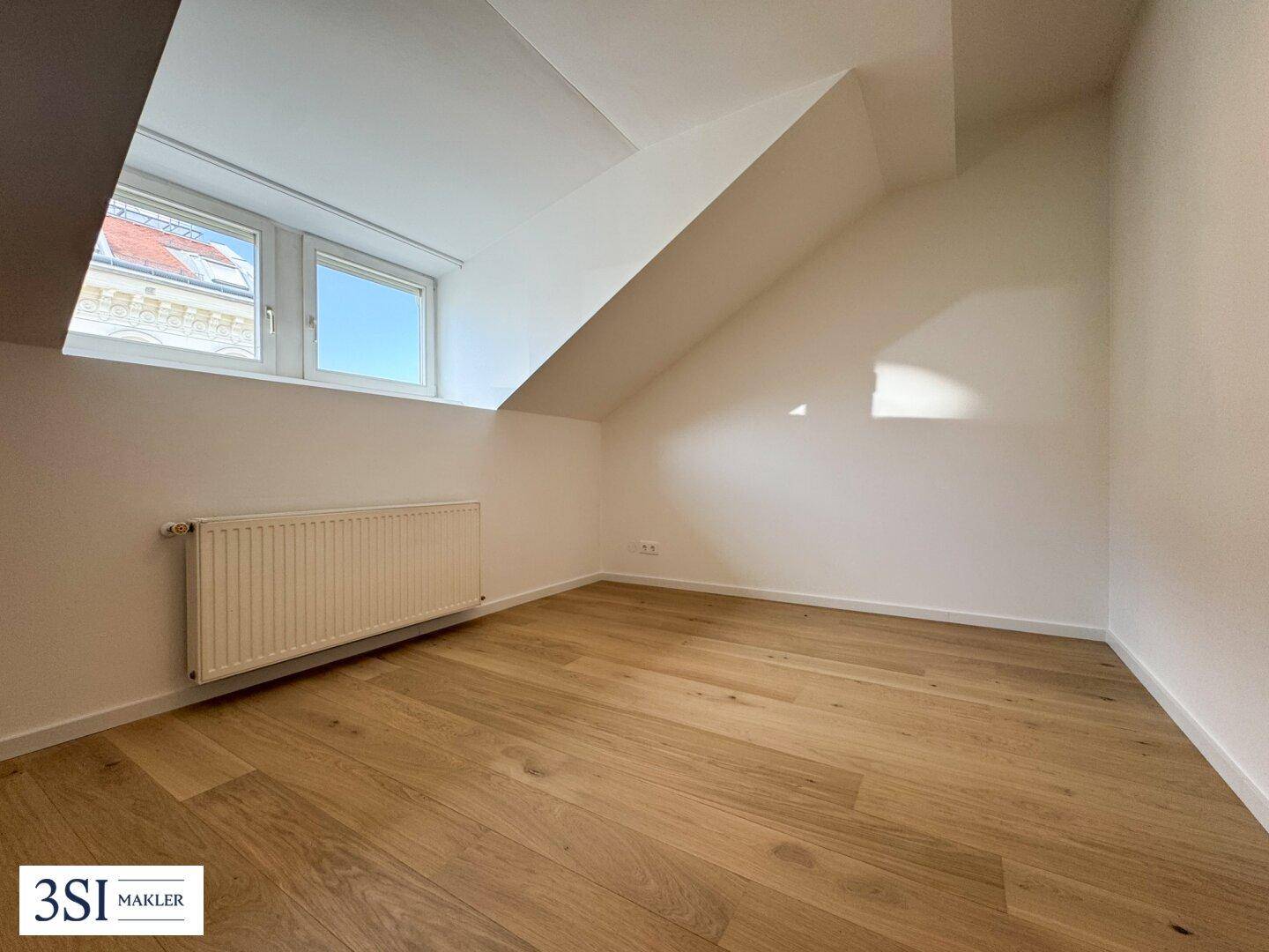 Helles Zimmer mit Holzboden und Dachschräge, bietet Potenzial für ein ruhiges Schlafzimmer.