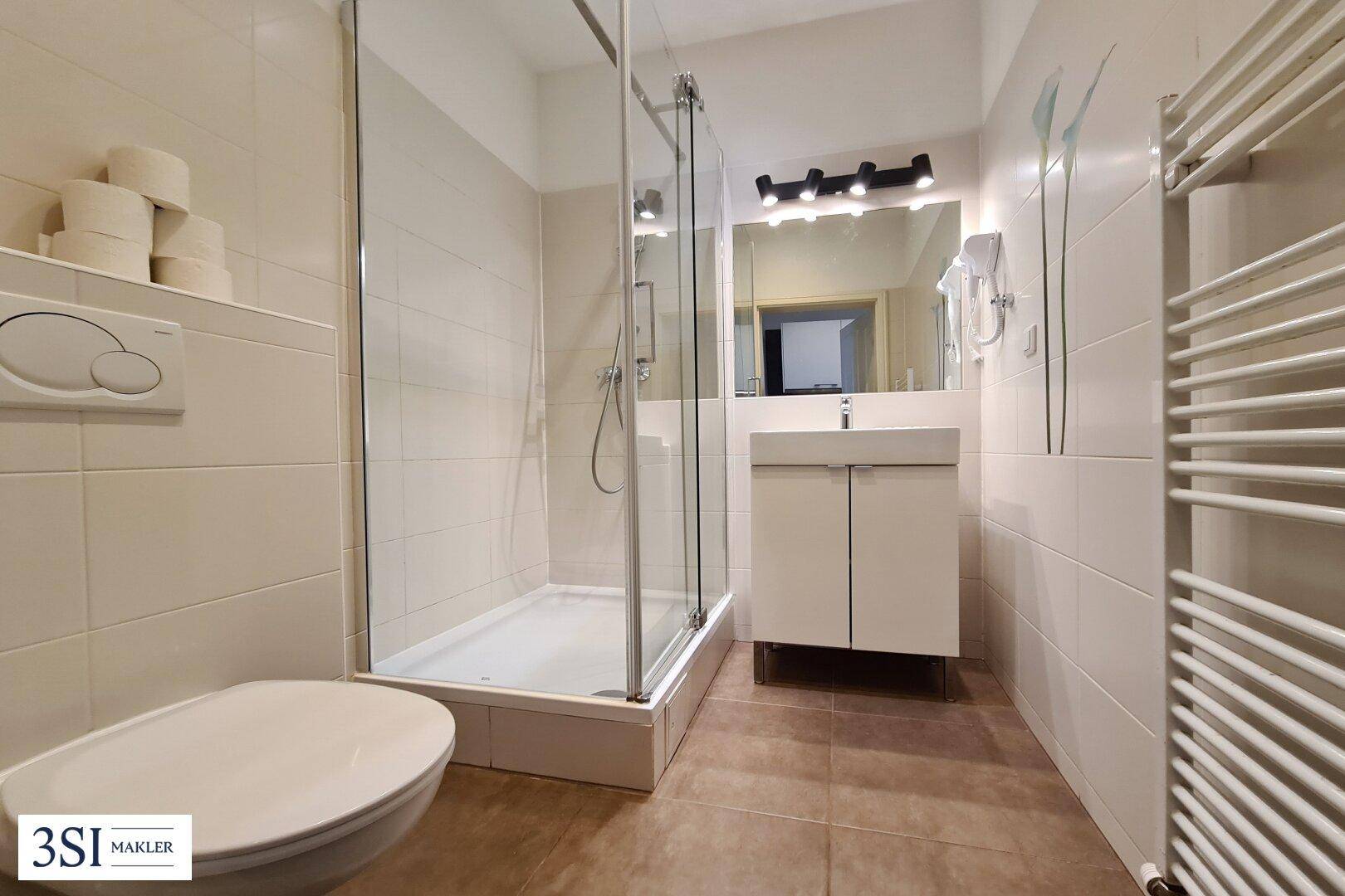 Modernes Badezimmer mit Duschkabine, WC, Waschbecken und beheiztem Handtuchhalter.