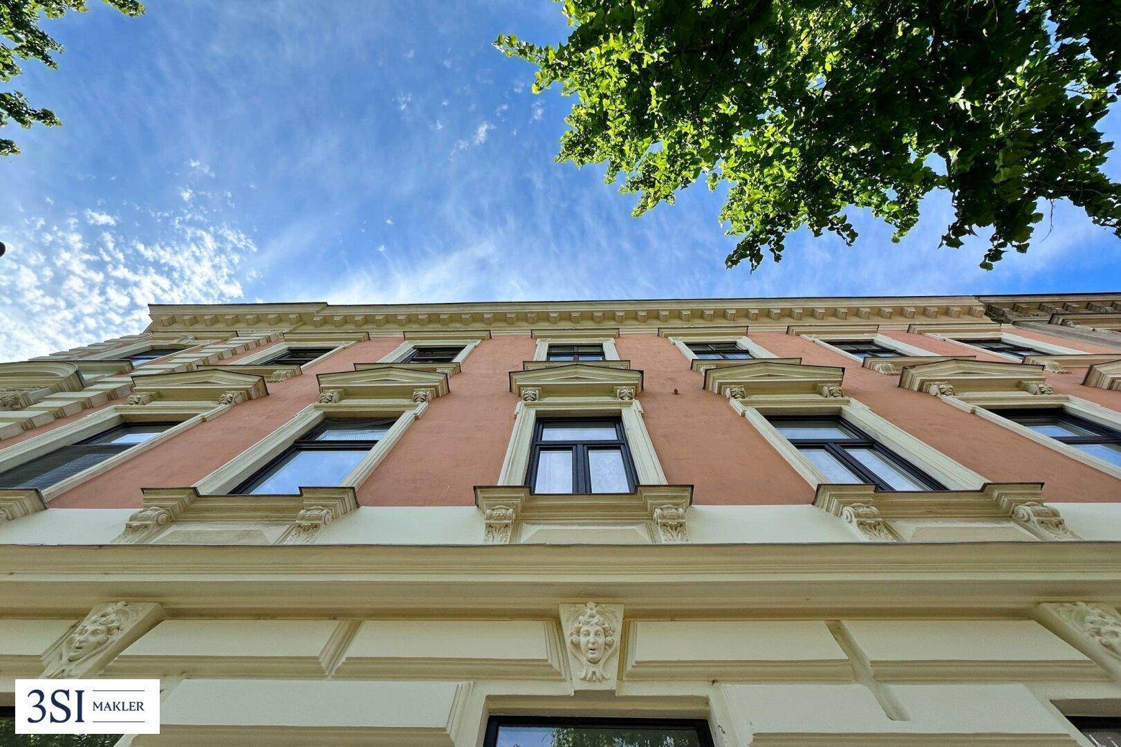 Historische Fassade eines Altbaus mit dekorativen Elementen und Fenstern.