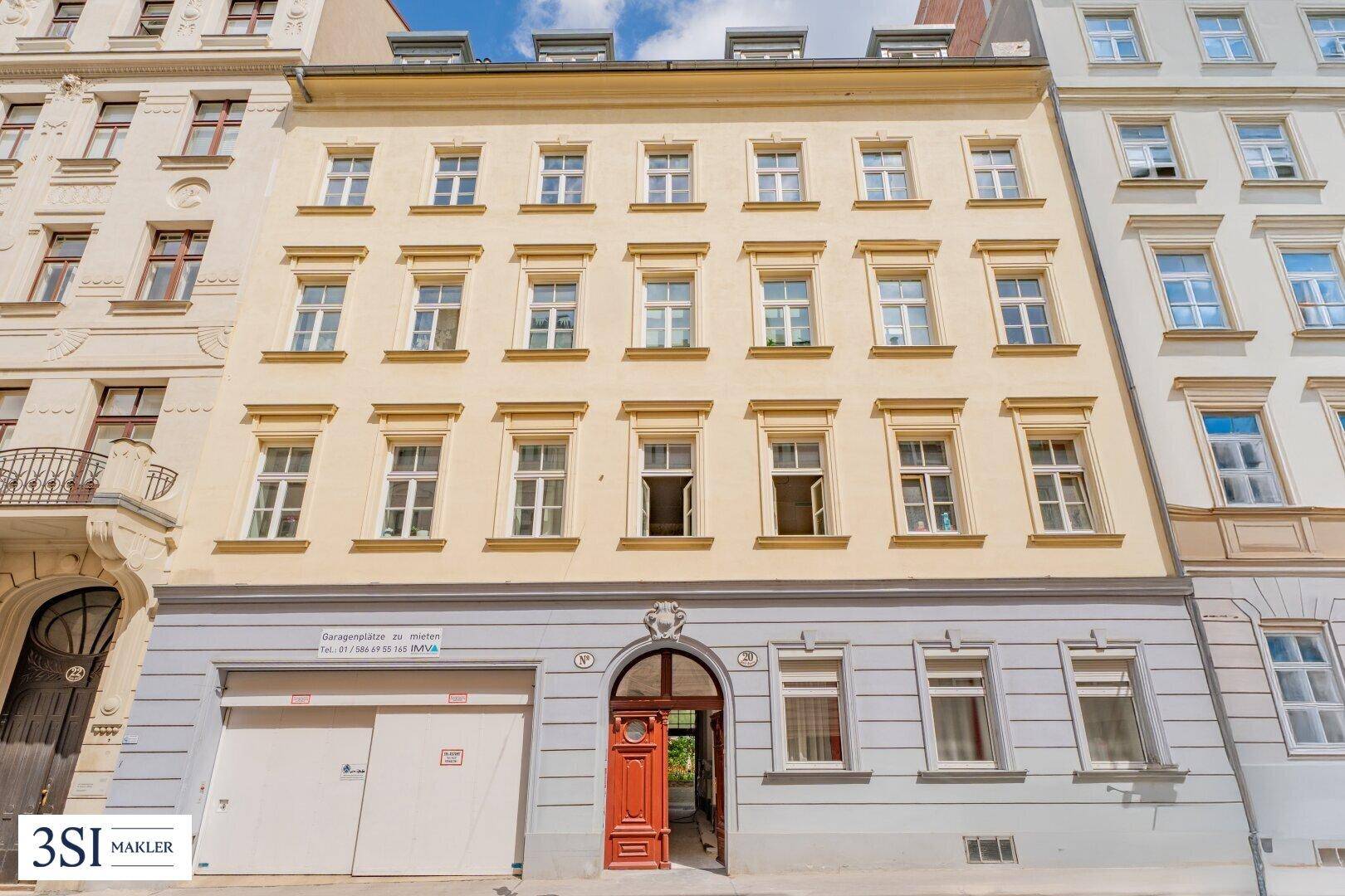 Klassische Fassade eines Altbaus in der Stadt mit vielen Fenstern und einer Garage im Erdgeschoss.