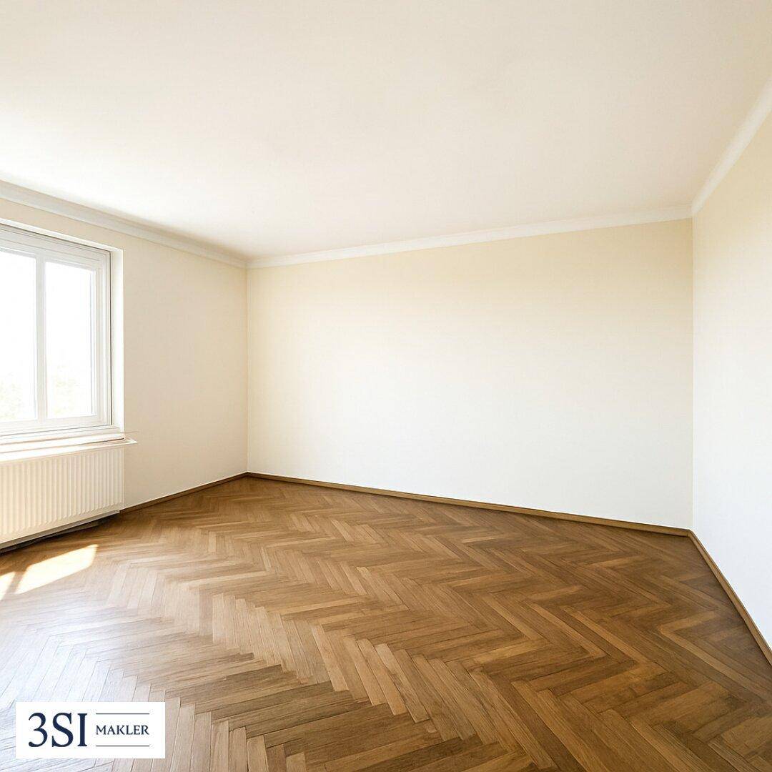 Leeres, helles Zimmer mit Fischgrätparkett und einem großen Fenster, das viel Licht hereinlässt.