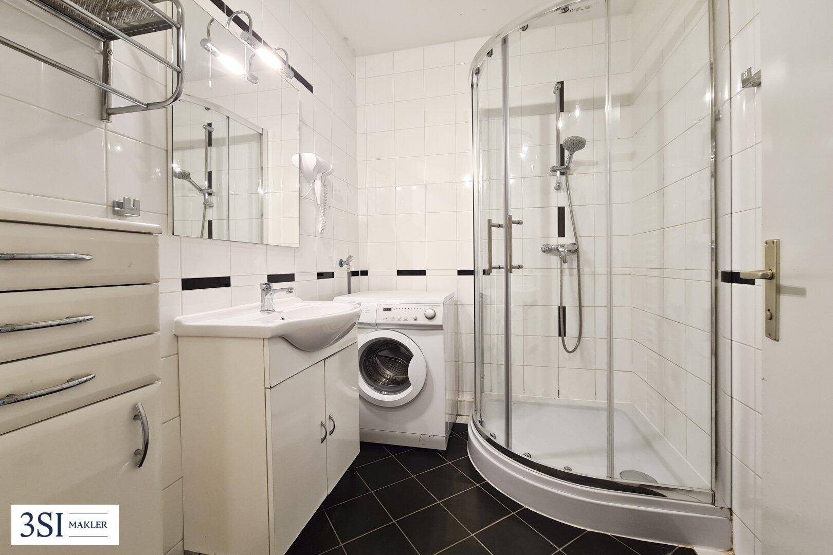 Funktionales Badezimmer mit Duschkabine, Waschbecken und Waschmaschine.
