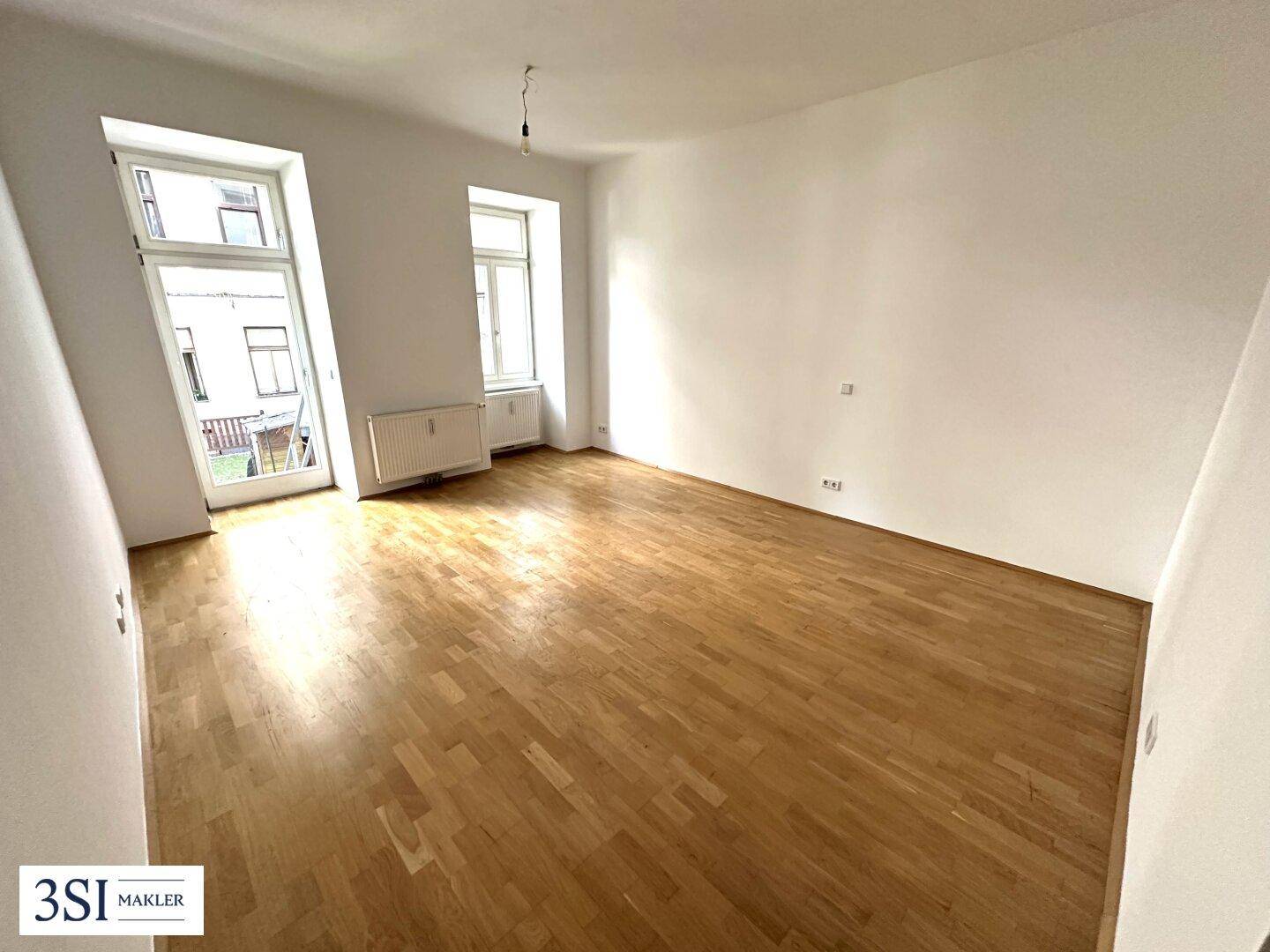 Geräumiges, unmöbliertes Zimmer mit Holzboden und großen Fenstern, bereit zur individuellen Gestaltung.