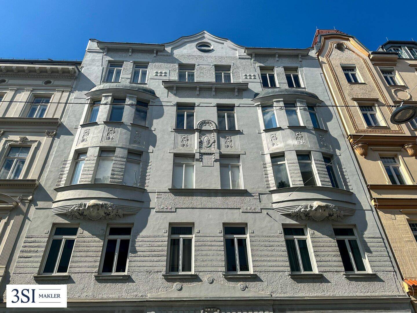Historische Fassade eines Mehrfamilienhauses mit Stuckelementen und Erkern.