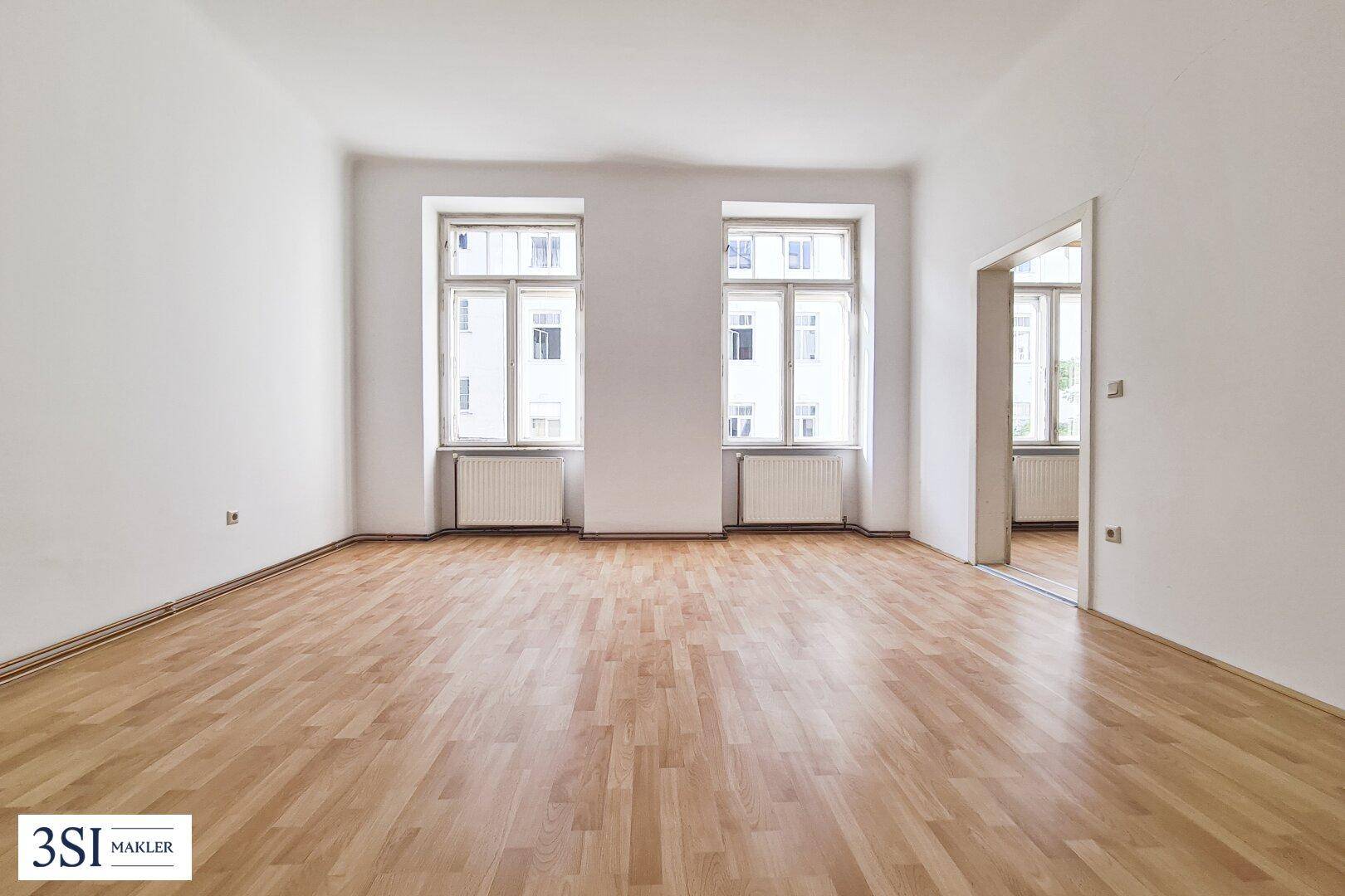 Geräumiges, leeres Zimmer mit Holzboden und zwei Fenstern, bereit zur Einrichtung.