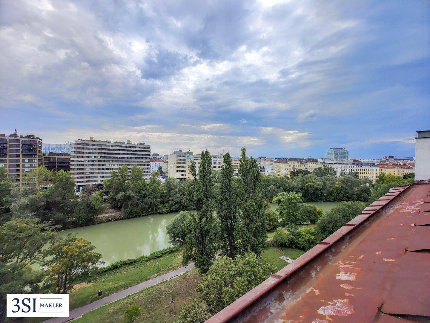 Panoramablick über den Fluss und die Stadt, mit einem Teil des Daches im Vordergrund.