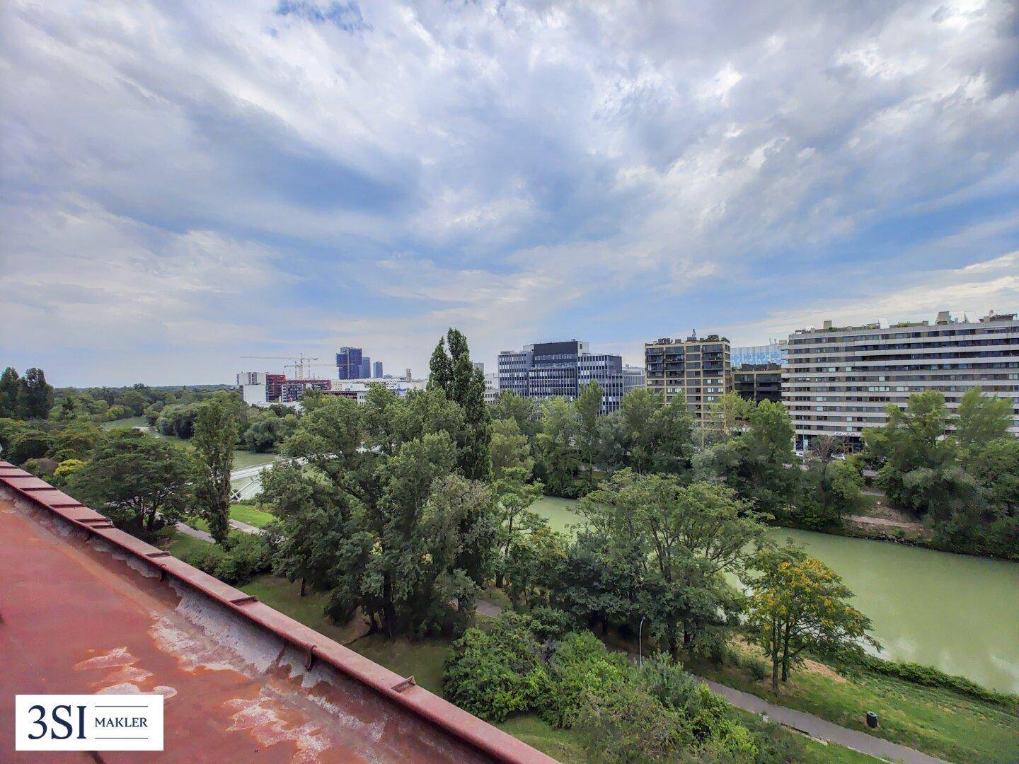 Weitläufiger Ausblick auf die Flusslandschaft und die städtische Bebauung am Horizont.