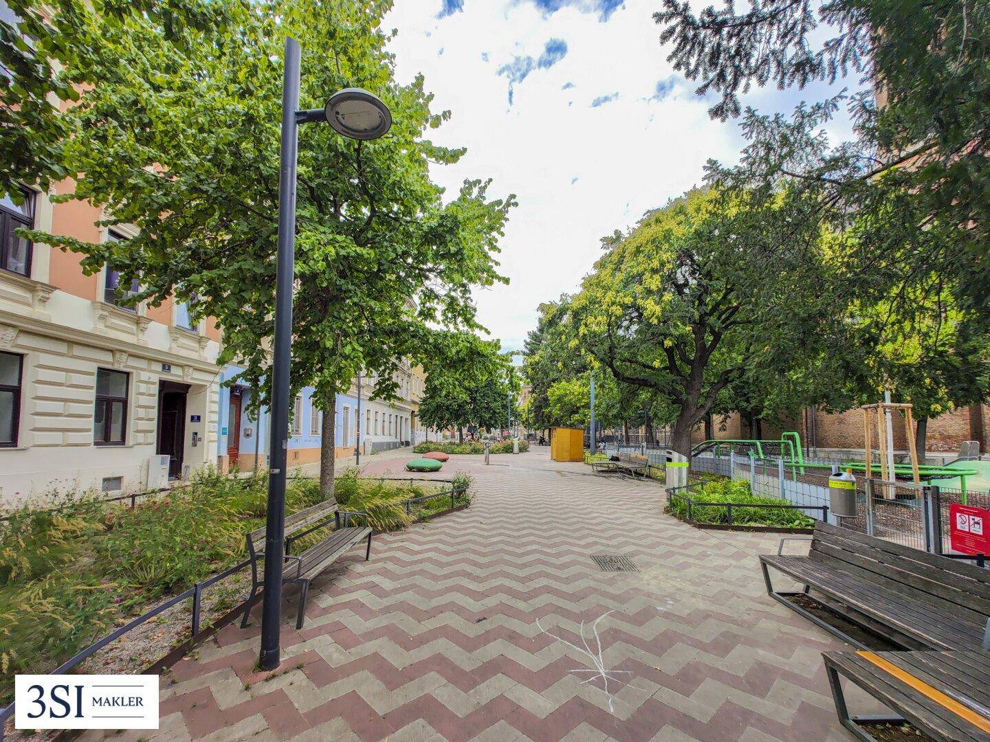 Grüne Allee mit Bänken und Bäumen, ideal für Spaziergänge in der Stadt.