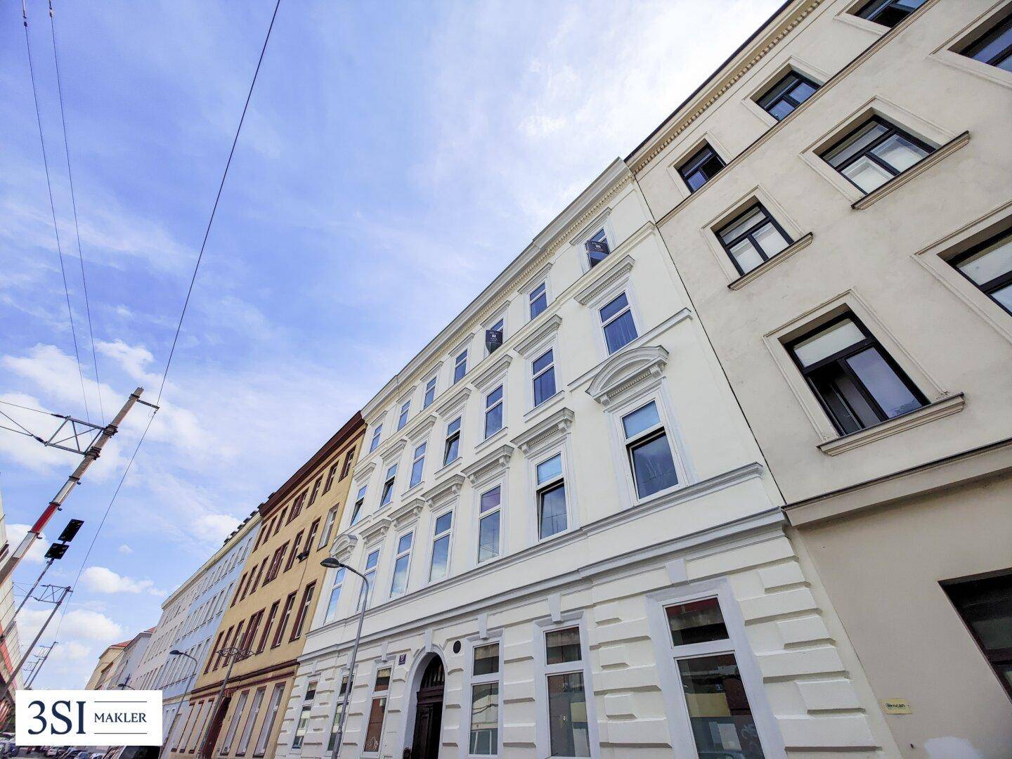 Historische Fassade eines Wohnhauses mit vielen Fenstern und klassischer Architektur.