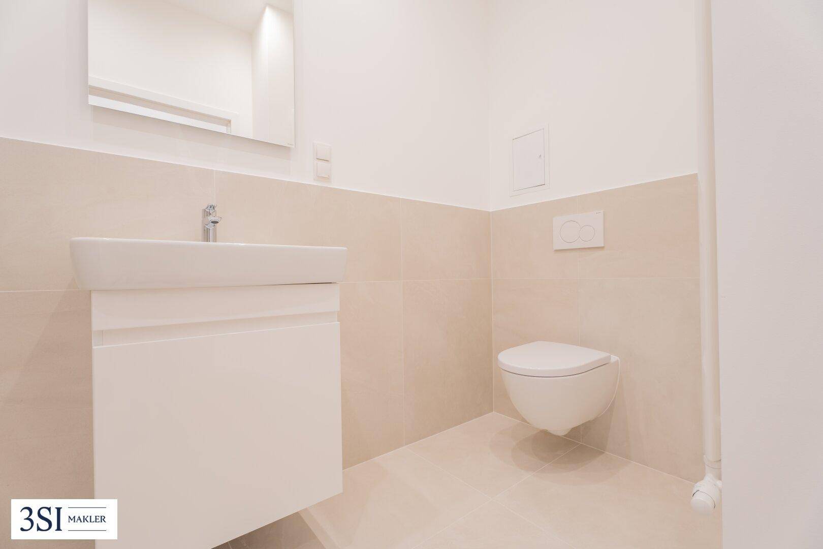 Helles WC mit wandhängender Toilette, Einzelwaschbecken und beigefarbenen Wandfliesen.
