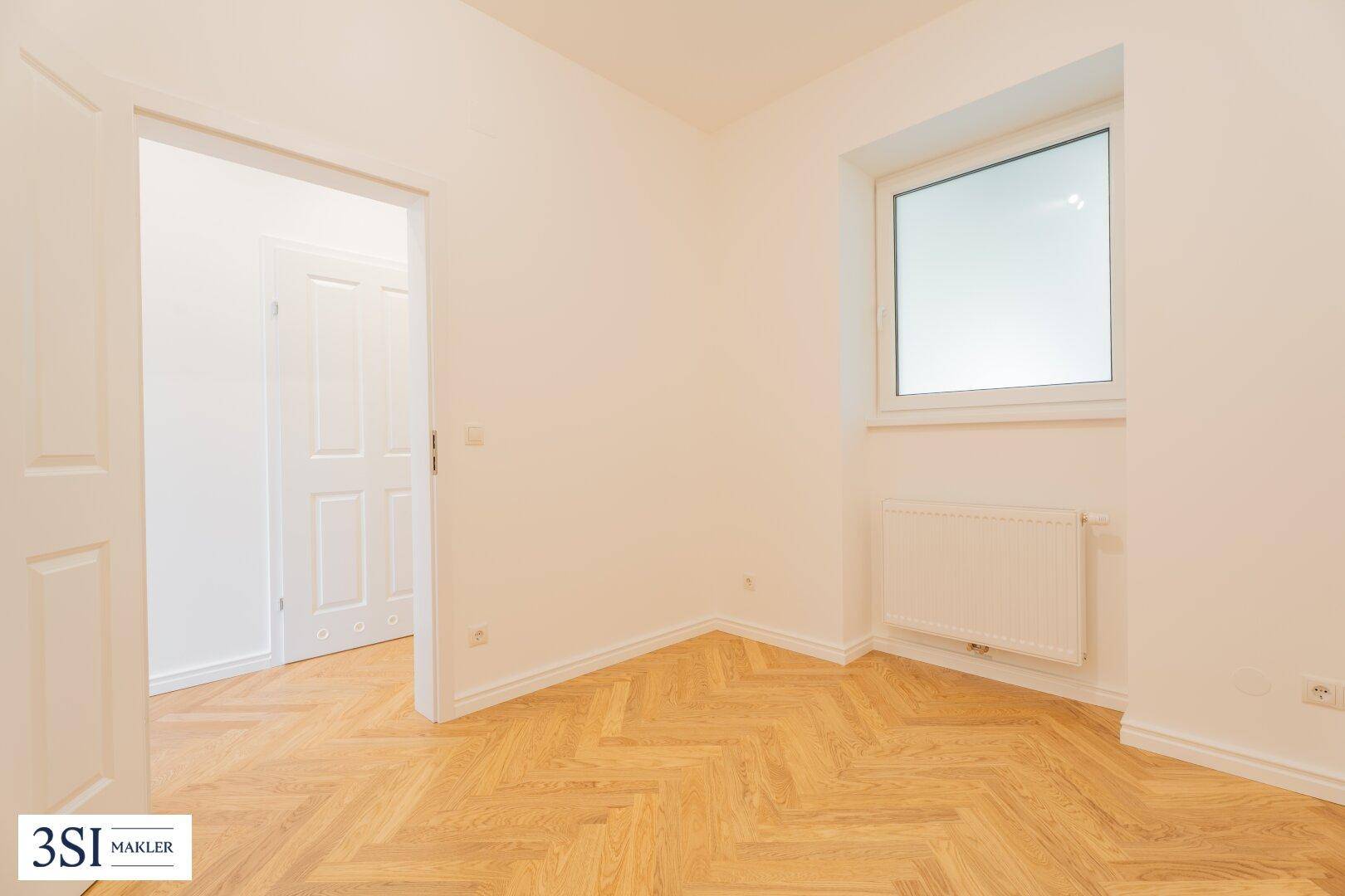 Gemütliches Zimmer mit Fischgrätparkett und einem Fenster, ideal als Schlaf- oder Arbeitszimmer.