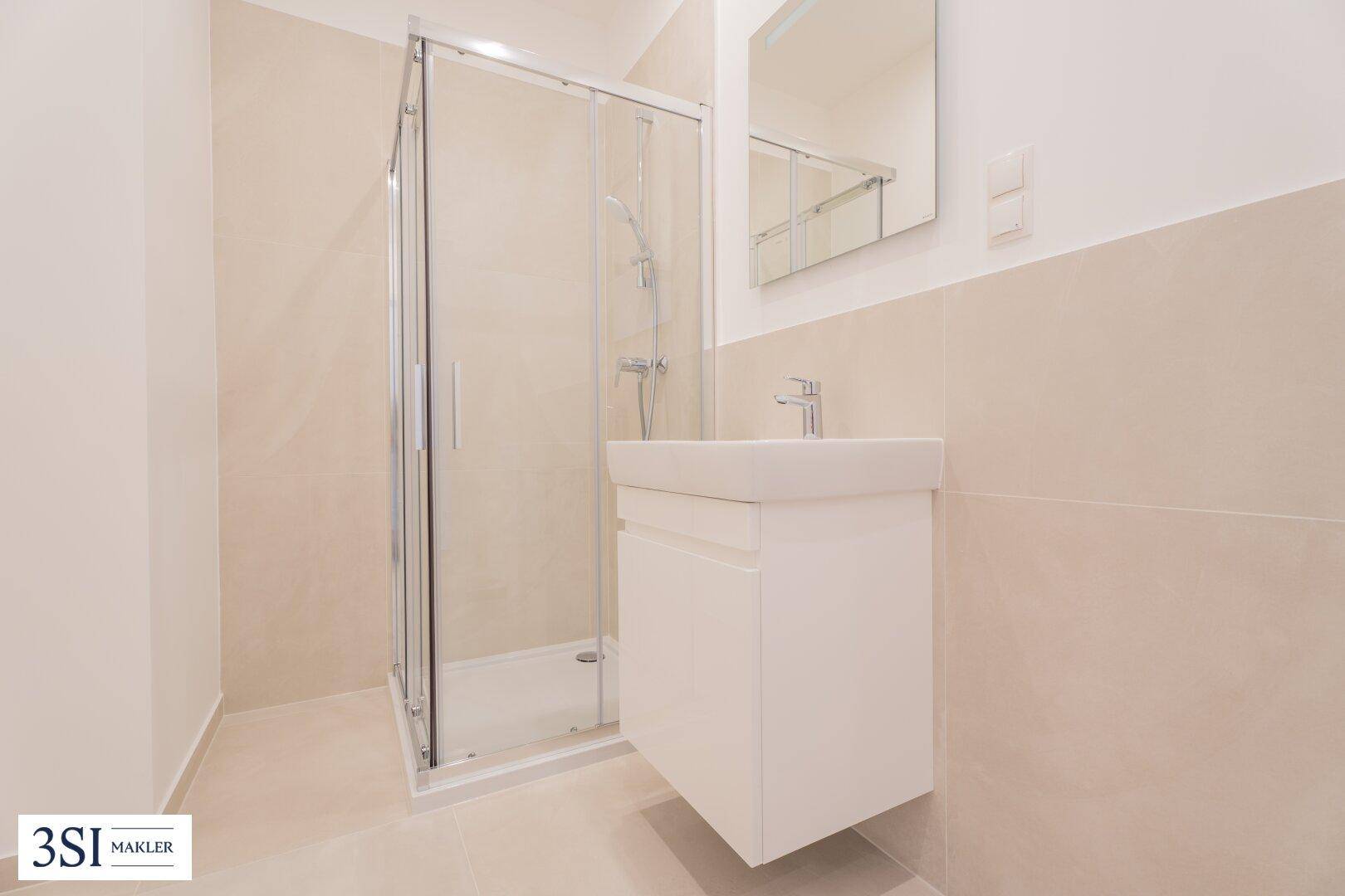 Modernes Badezimmer mit begehbarer Dusche, Waschbecken und hellen Fliesen an Wänden und Boden.
