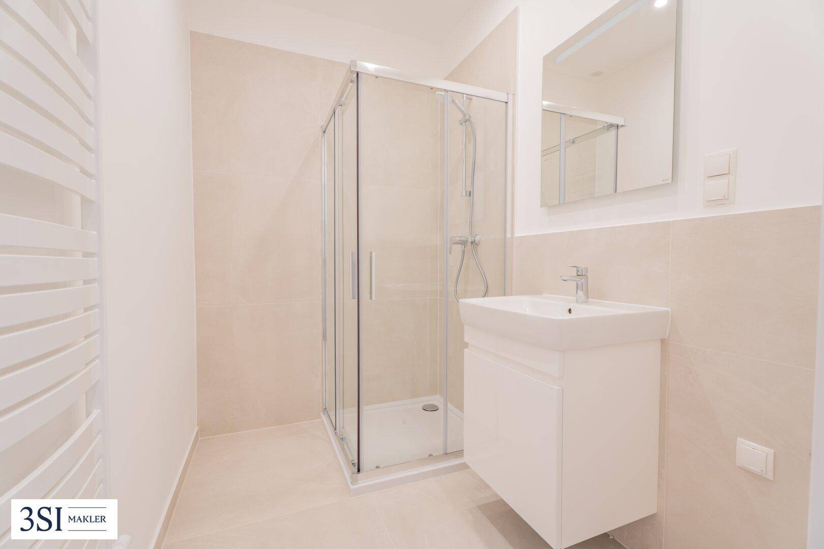 Modernes Badezimmer mit Duschkabine, Waschbecken und beheiztem Handtuchhalter.
