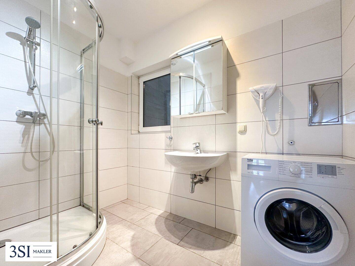 Modernes Badezimmer mit Duschkabine, Waschbecken, Spiegelschrank und einer Waschmaschine.