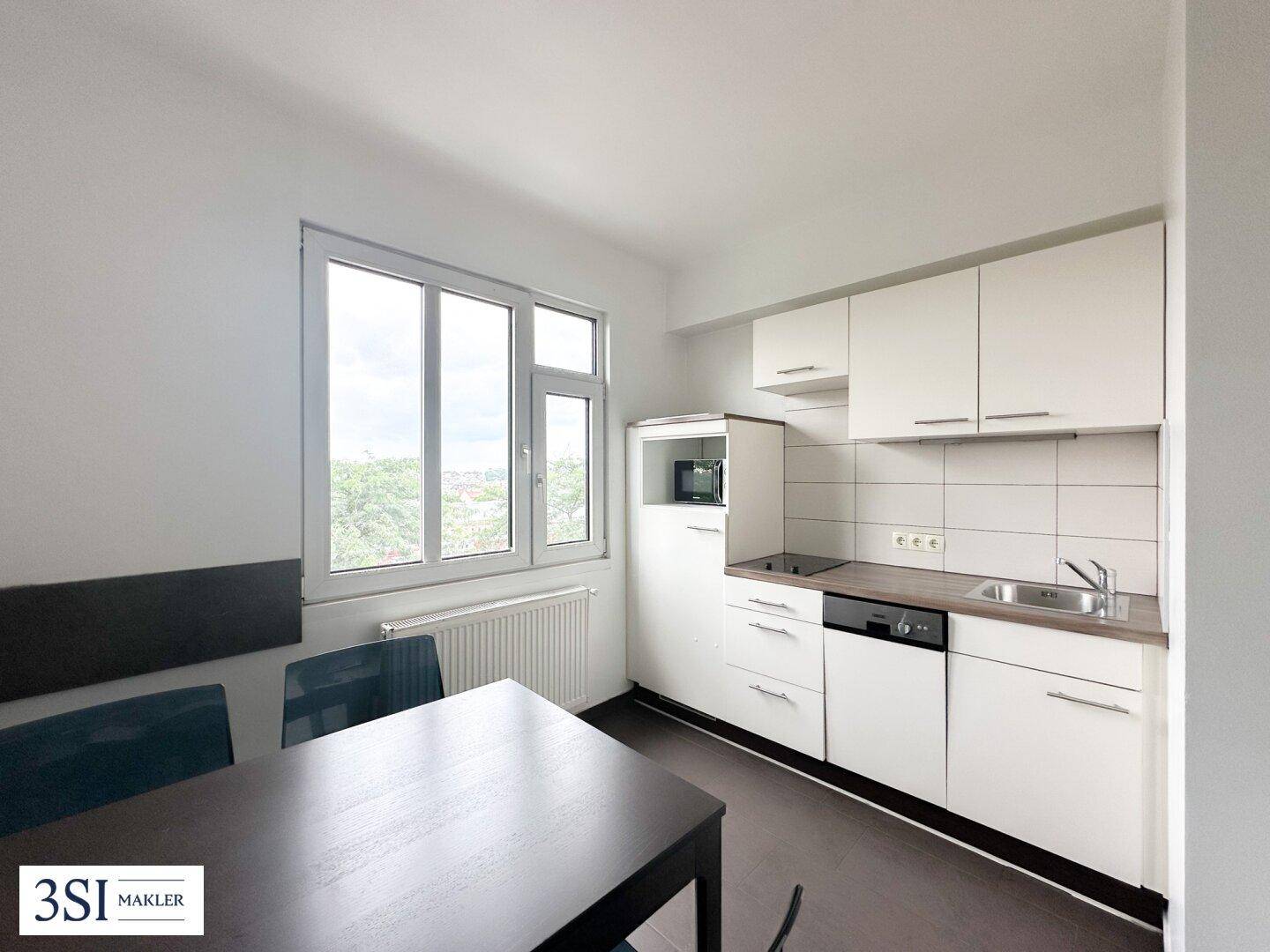 Funktionale Küche mit weißen Schränken, integriertem Geschirrspüler und Essbereich am Fenster.