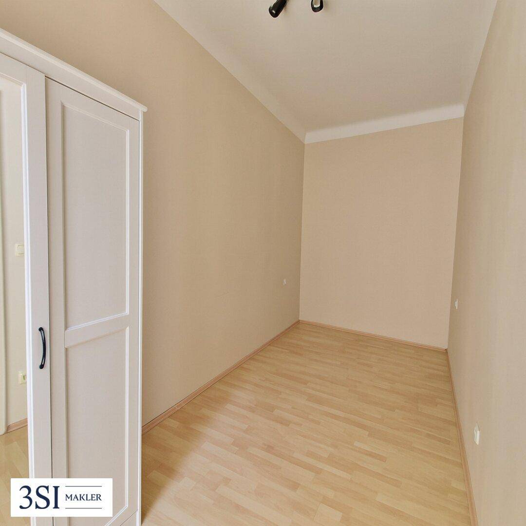 Leeres Zimmer mit hellem Parkettboden und weißem Kleiderschrank, ideal als Schlaf- oder Gästezimmer.