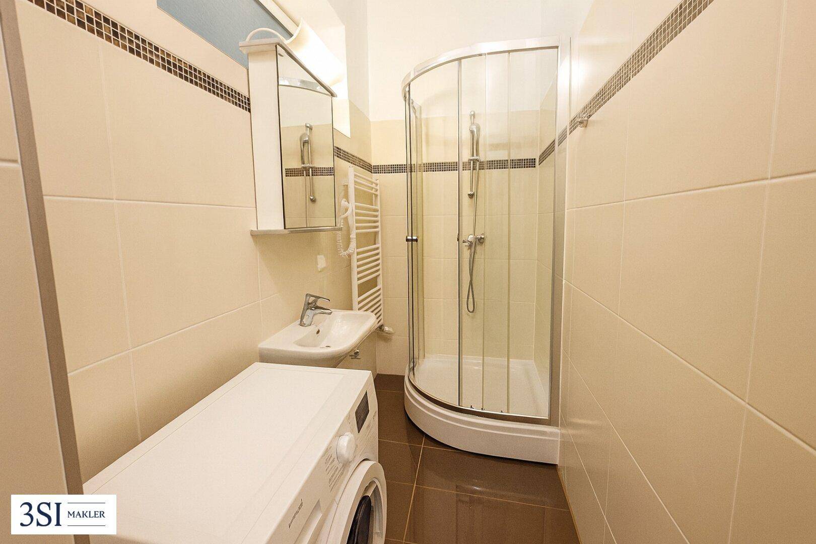 Modernes Badezimmer mit Duschkabine, Waschbecken, Waschmaschine und beheiztem Handtuchhalter.