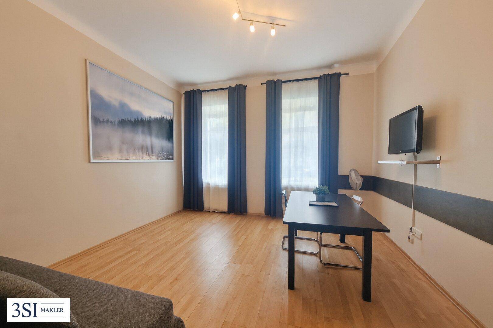 Gemütliches Wohnzimmer mit Holzboden, einem Esstisch und einem Wandfernseher.